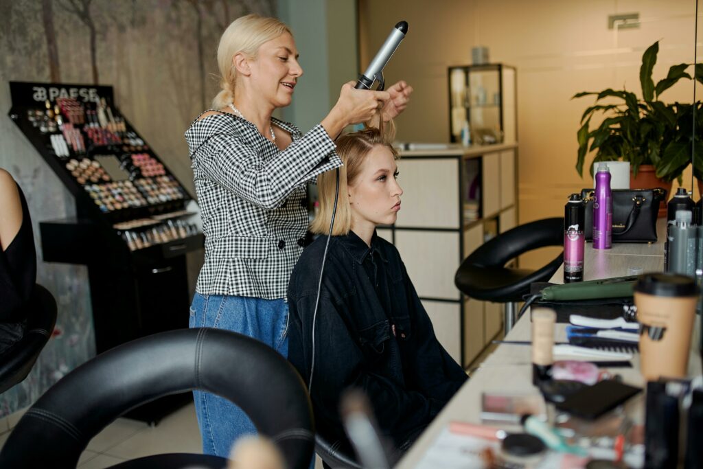 pexels-photo-5368626-5368626 Side view of adult hairstylist straightening hair of client with iron in hairdressing salon